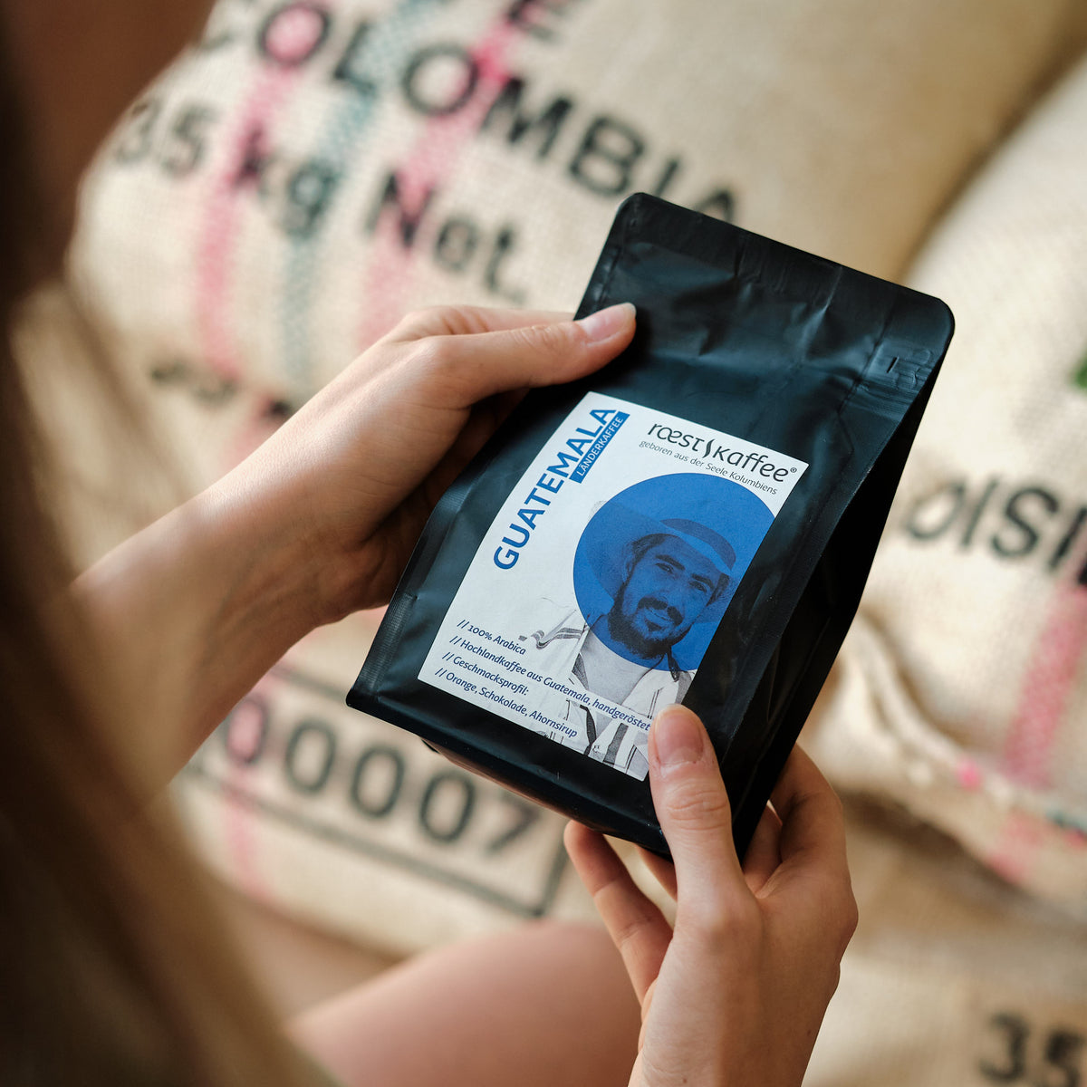 Hält eine 250g Kaffeepackung in der Hand, Sorte: Guatemala,  Dieser Kaffee überzeugt durch seinen besonderen Geschmack, der durch die seltenen Regenfälle in der Anbauregion entsteht. Ein Muss für Kaffeeliebhaber und Aficionados!
